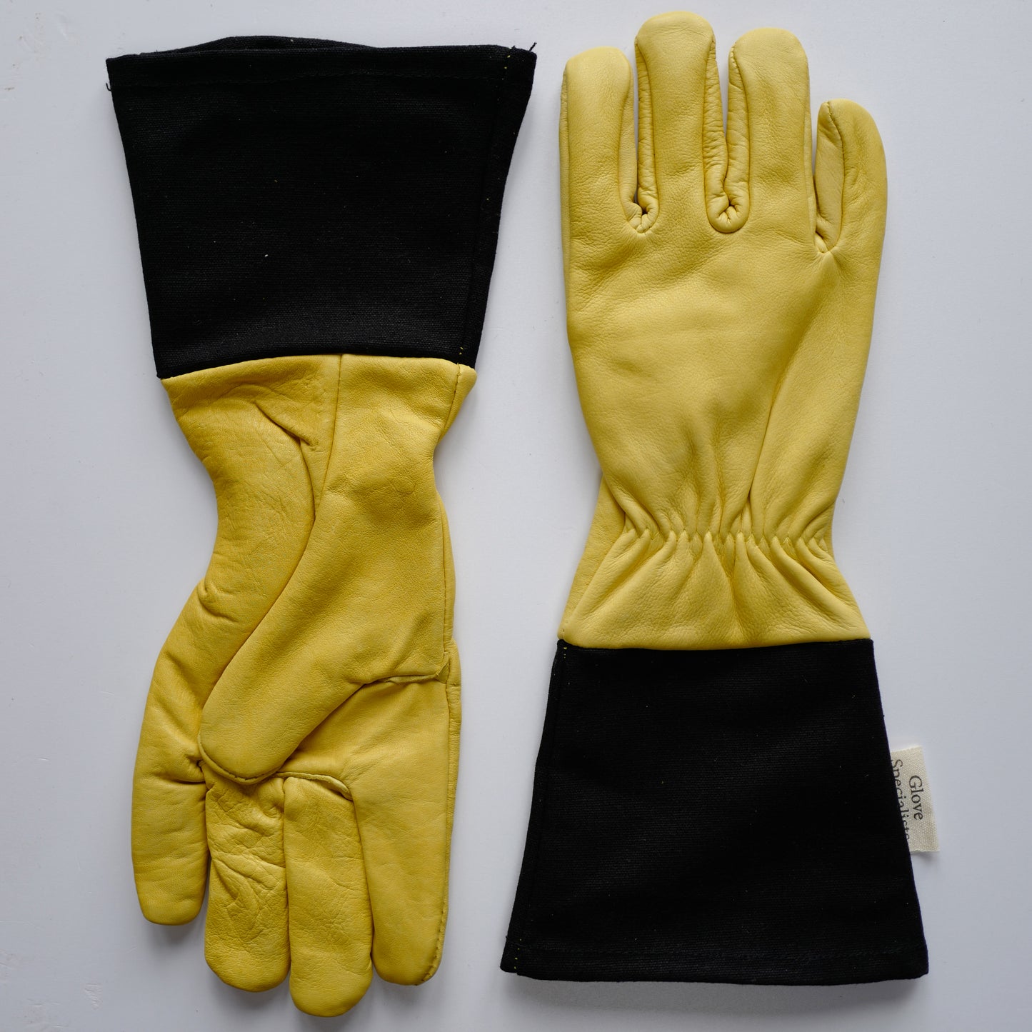 Yellow lined leather gardening gloves with black cotton canvas short cuffs, elasticated wrists, and reinforced palms, designed for thorn protection and dexterity.